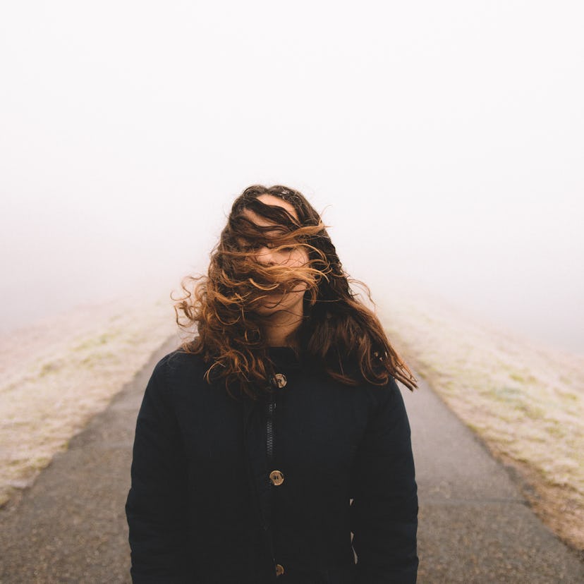 young woman poses as her hair blows in the wind as she thinks about the jupiter-neptune conjunction ...