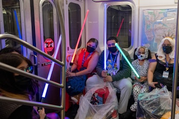 NEW YORK, NEW YORK - OCTOBER 10: Cosplayers in costumes wield lightsabers on a subway at the 34th St...
