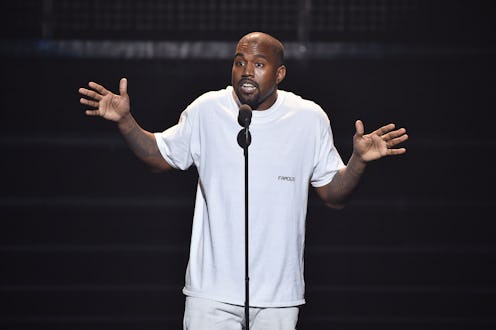 Kanye West during a public speech in a white shirt and white pants
