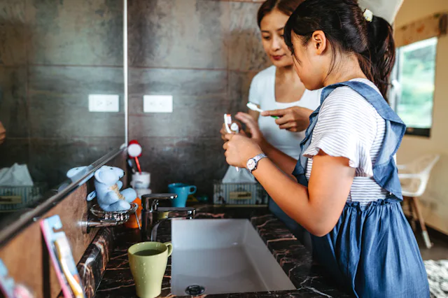Asian girl with her mother brushing teeth in the bathroom