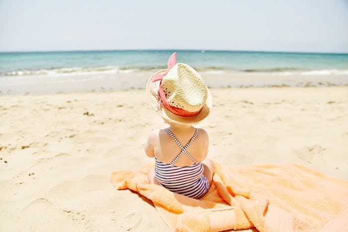 baby girl sitting on beach wearing hat
