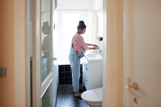 Side view of pregnant woman using disinfectant while washing hands at sink