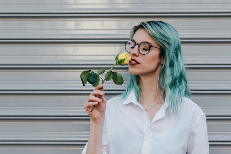 Young woman smelling a yellow rose, daydreaming about the April 11, 2022 weekly horoscope for her zo...