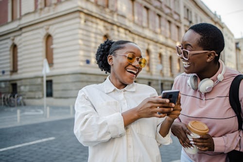 A woman shows her friend a photo on her phone. Astrologers reveal the best careers for gemini zodiac...