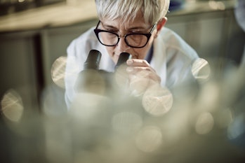 female scientist doing a research through a microscope in laboratory