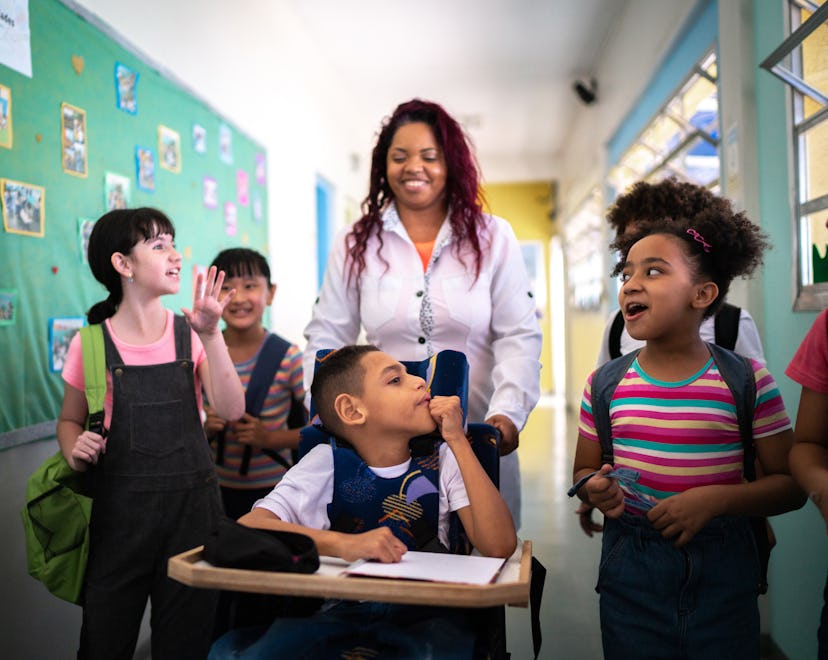 Teacher and students walking in the corridor at school - including a person with special needs
