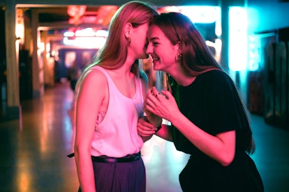 Two young women laughing with each other, discussing the April 18, 2022 weekly horoscopes for their ...