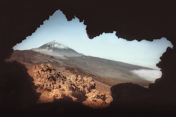Mountain and rocks landscape in El Teide National Park in Tenerife through a small cave with blue sk...