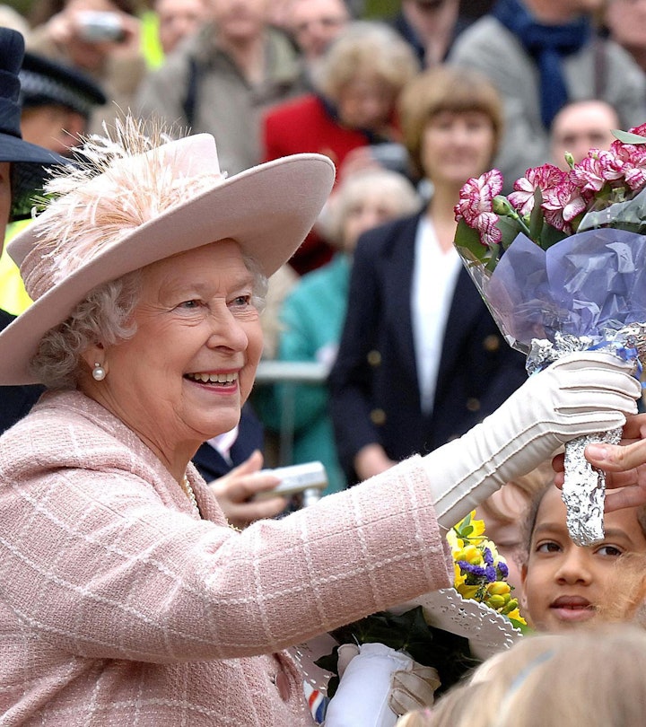 Queen Elizabeth II is presented with flowers during a walkabout outside Manchester Cathedral after a...