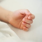 Close-up of a child's hand on white bed linen