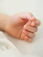 Close-up of a child's hand on white bed linen