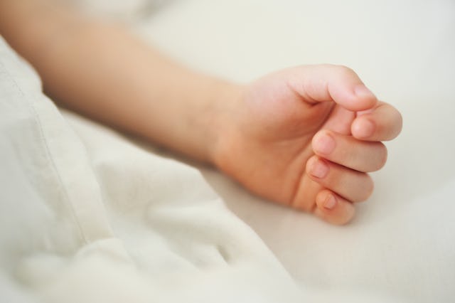 Close-up of a child's hand on white bed linen