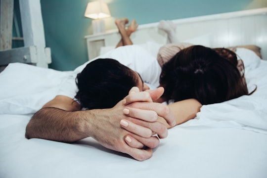 Heterosexual couple holding hands in bed