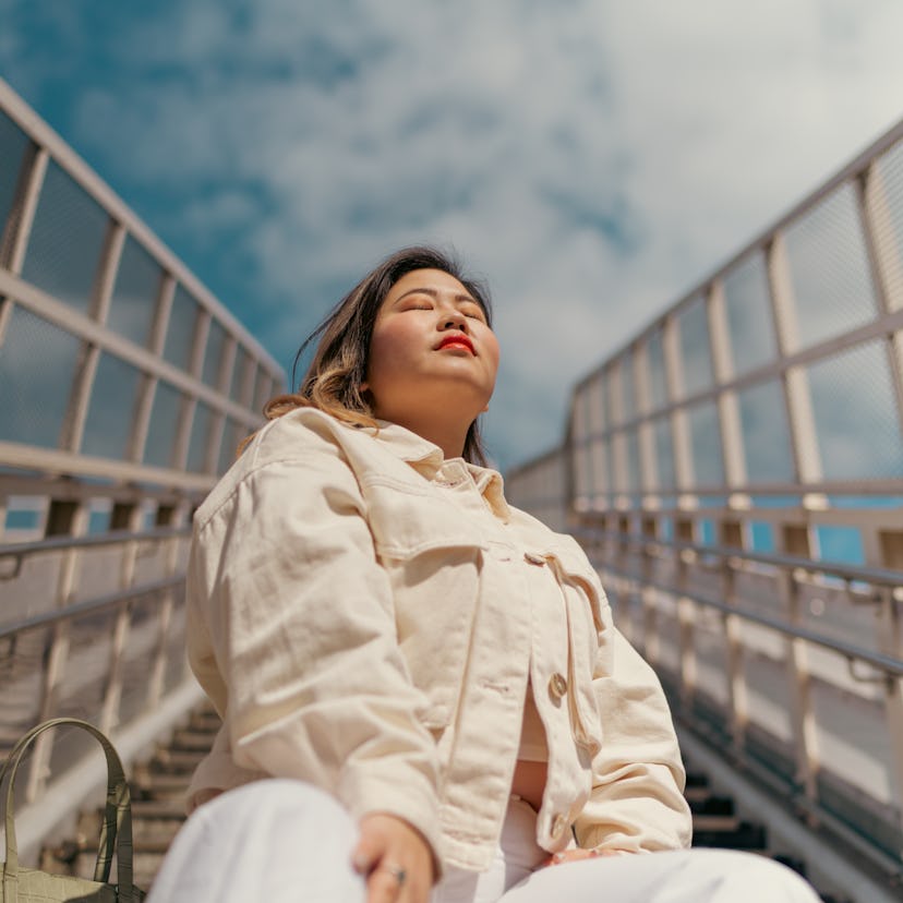 young woman closes eyes as she reflects on how the April 2022 Black Moon solar eclipse will affect h...