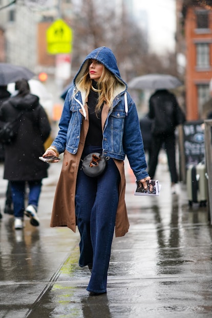 NEW YORK, NEW YORK - FEBRUARY 10: A guest wears a blue denim jacket with hood and white wool inner l...