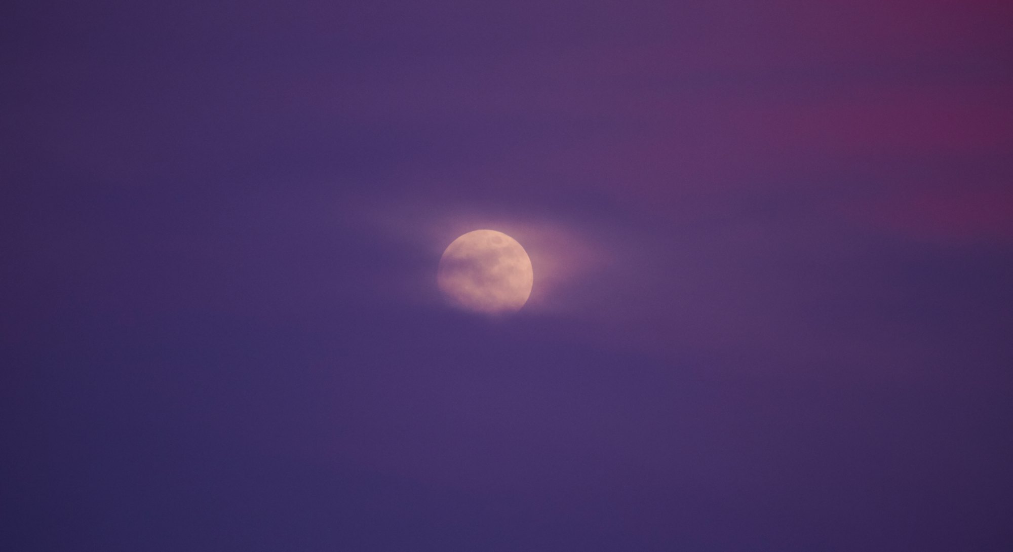 Nighttime sky with clouds and bright full moon. The April full "Pink" moon peaks on Apr. 16.