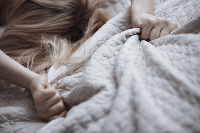 Blond woman grabbing bed linen taking advantage of a higher libido during pregnancy.