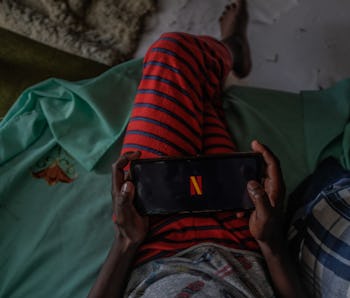 NAIROBI, KENYA - SEPTEMBER 23: A young boy prepares to watch a movie on Netflix using an android sma...