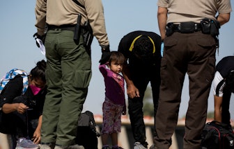 TOPSHOT - A girl looks on as migrants from Guatemala remove their shoelaces as they are initially pr...