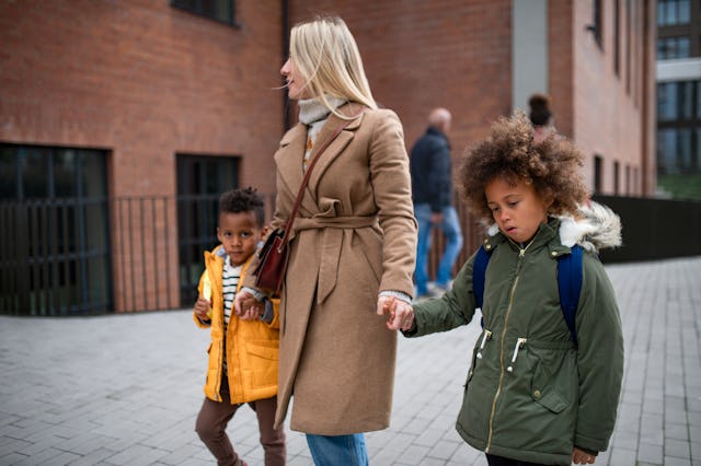 Mother with her two small little children on the way to school.