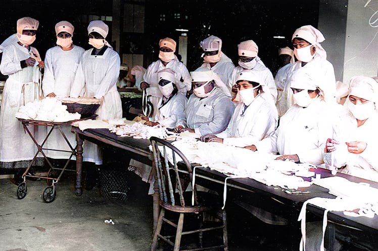 Red Cross volunteers assemble gauze face masks to prevent the spread of influenza while wearing mask...