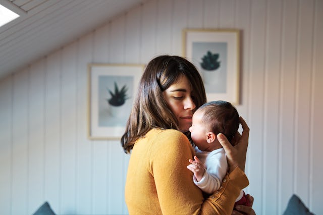 Side view of new mother comforting her newborn while crying. Baby getting used to noises and lights ...
