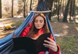 A woman reads a book in a hammock. Your may 2022 full flower moon lunar eclipse horoscope. How the m...