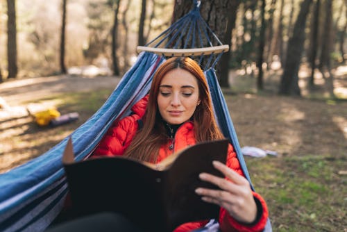 A woman reads a book in a hammock. Your may 2022 full flower moon lunar eclipse horoscope. How the m...