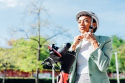 A woman straps on a bike helmet. The May 2022 Full Flower Moon Lunar Eclipse Will Affect These Zodia...
