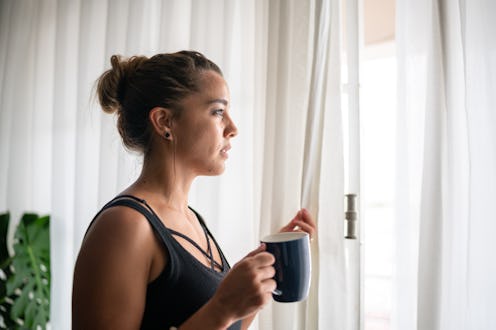 Contemplative woman drinking coffee or tea at home. Here's your may 12 zodiac sign daily horoscope f...