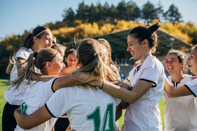 Group of women, women soccer team celebrating victory on soccer field.