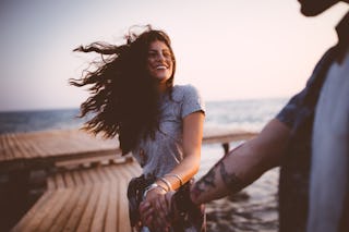 Young romantic hipster couple on summer island holidays holding hands and having fun on jetty