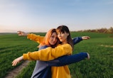 Two women hugging in a field in front of the blue sky at the sunset. Common Taurus-Gemini cusp trait...