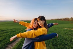 Two women hugging in a field in front of the blue sky at the sunset. Common Taurus-Gemini cusp trait...