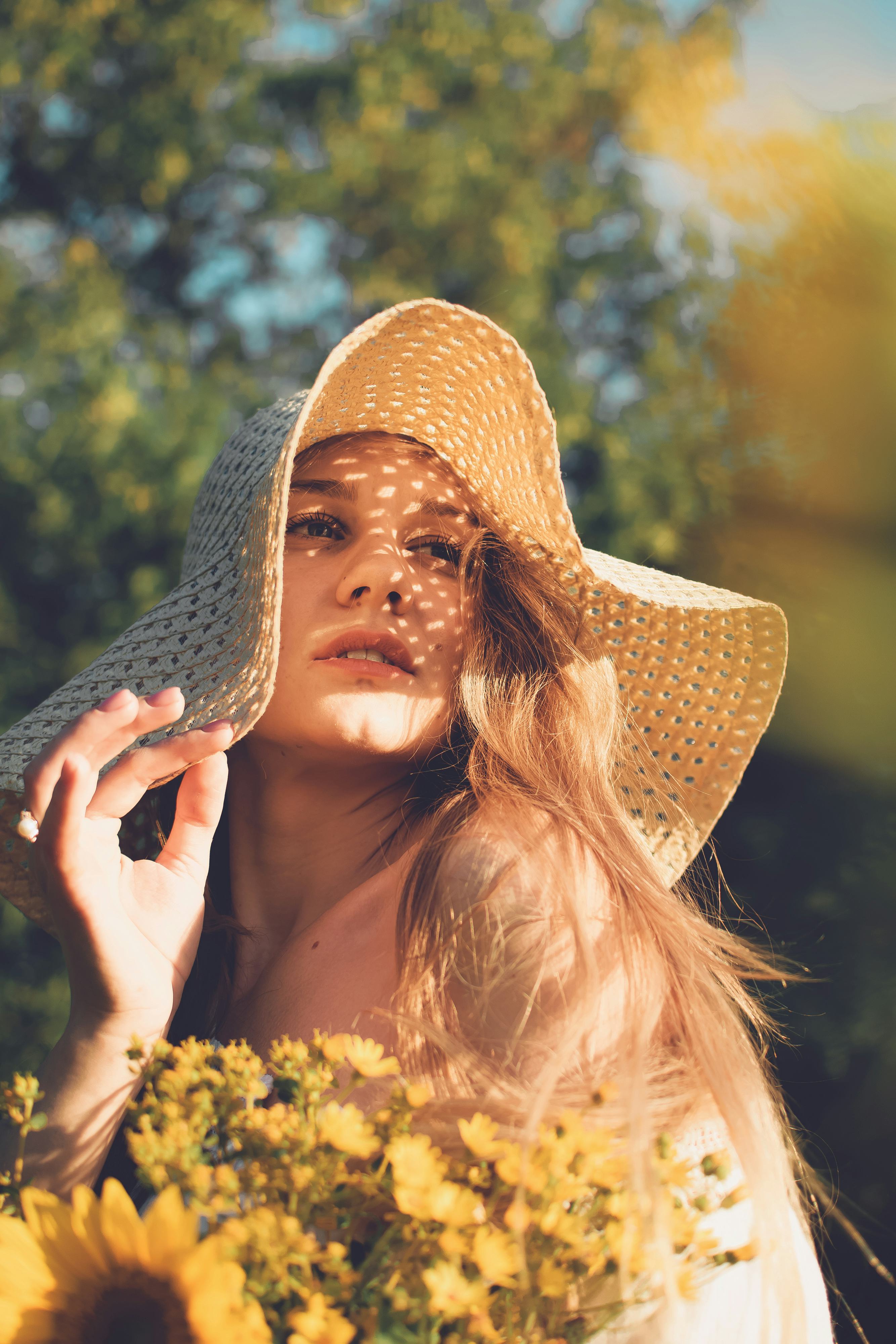 young woman holding a bouquet of flowers gazes into sunlight as she thinks about the may 2022 new mo...