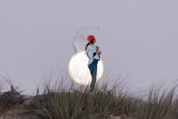 A woman stands with a clear umbrella in front of the full moon. These may 2022 full flower moon  rit...
