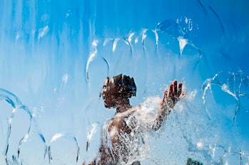 TOPSHOT - A boy walks through a waterfall on July 25, 2016 while playing in the water at The Yards P...