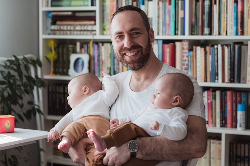 Cheerful man with twin baby boys in his arms relaxing at home/Instagram captions for when baby says ...