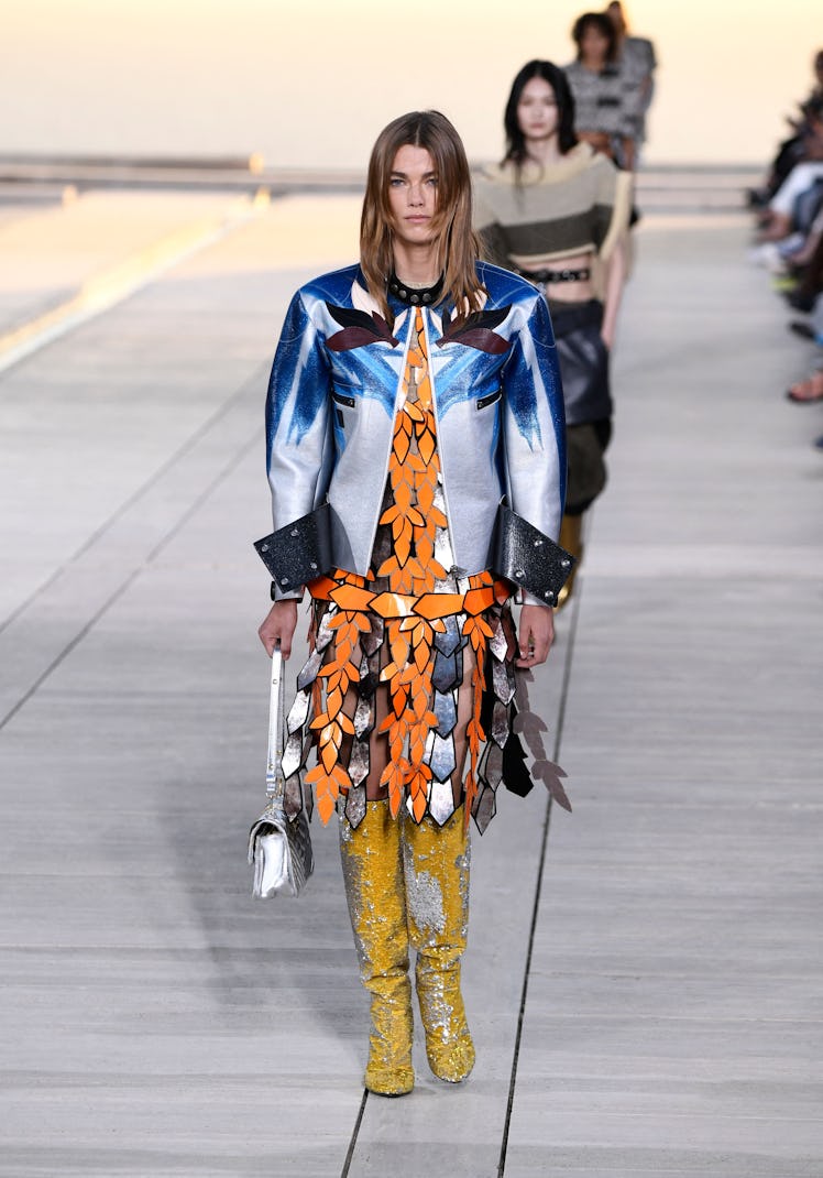 A model walking the runway for the Louis Vuitton's 2023 Cruise Show in an orange and silver dress