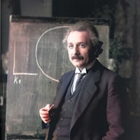 Half-length portrait of scientist Albert Einstein standing at chalkboard, 1921. Note: Image has been...