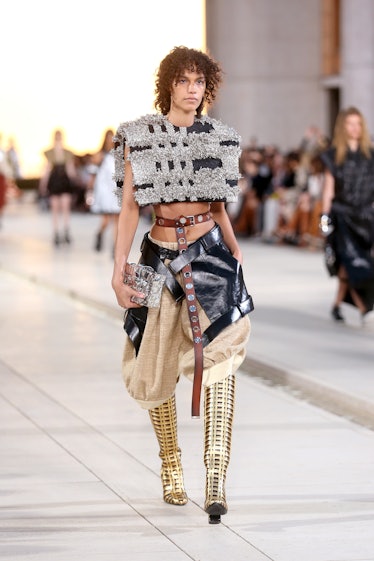A model walking the runway for the Louis Vuitton's 2023 Cruise Show in silver cotton top and black a...