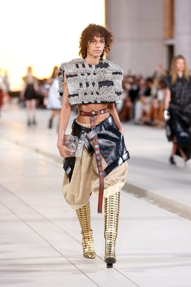 A model walking the runway for the Louis Vuitton's 2023 Cruise Show in silver cotton top and black a...