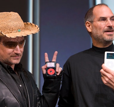 Bono, left, of the band U2, and Apple Computers Inc. Chief Executive Steve Jobs, right, hold up Appl...