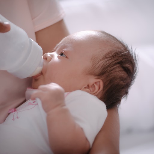 Newborn baby is fed from a bottle.