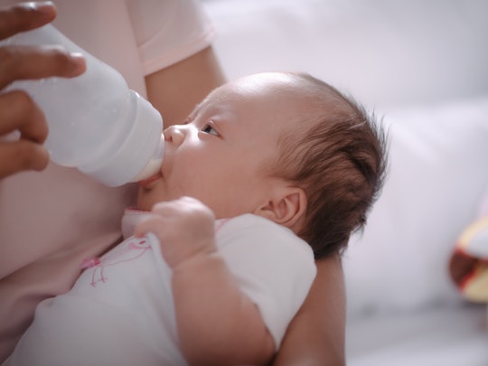 Newborn baby is fed from a bottle.