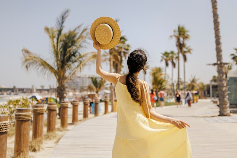 Back of Woman walking on the beach looking at the sun