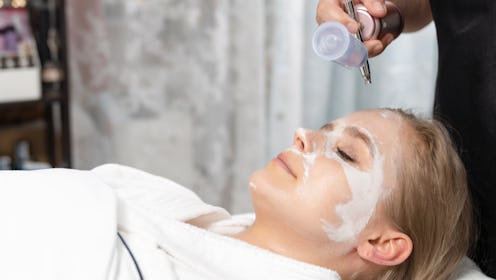 Close up of female face getting healthy clay mask by beautician