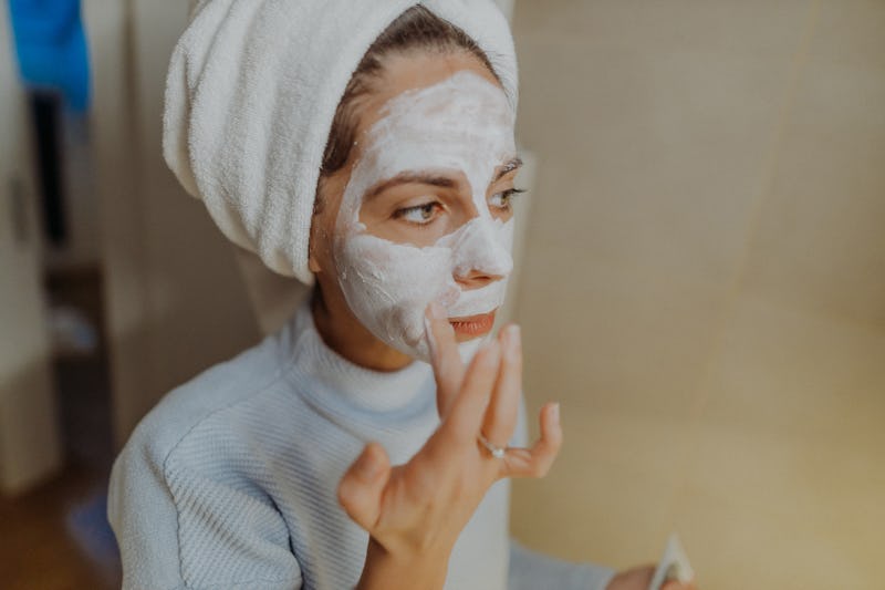 Young woman applying facial mask