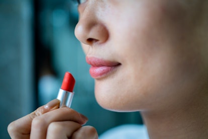 A young woman is putting on lipstick