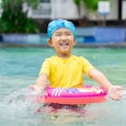 Cute little girl playing in a pool with a bright swimsuit. A new study found that bright neon colors...
